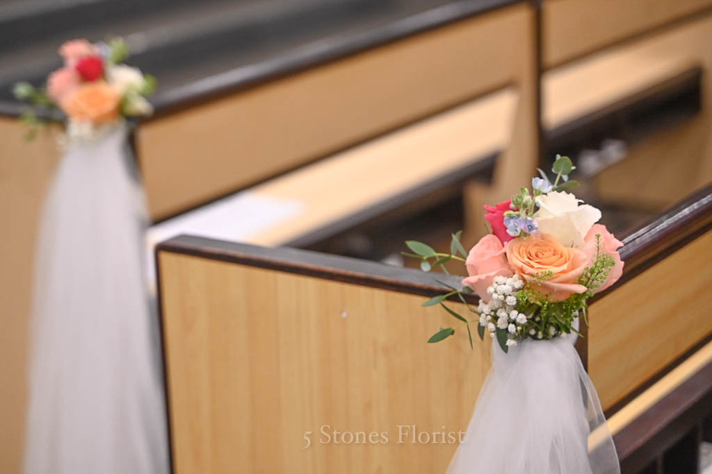 Pew posies with white sashes for a spring church wedding ceremony