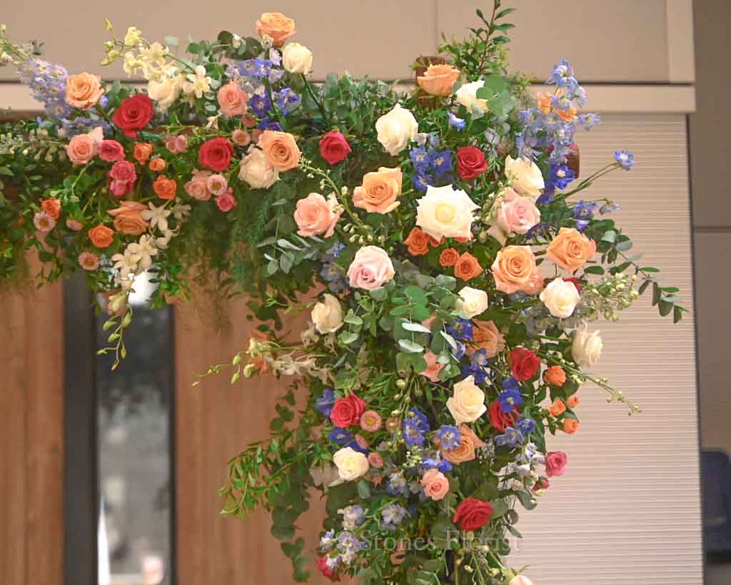 Colourful spring wedding floral arch at Grace Baptist Church entrance by 5 Stones Florist